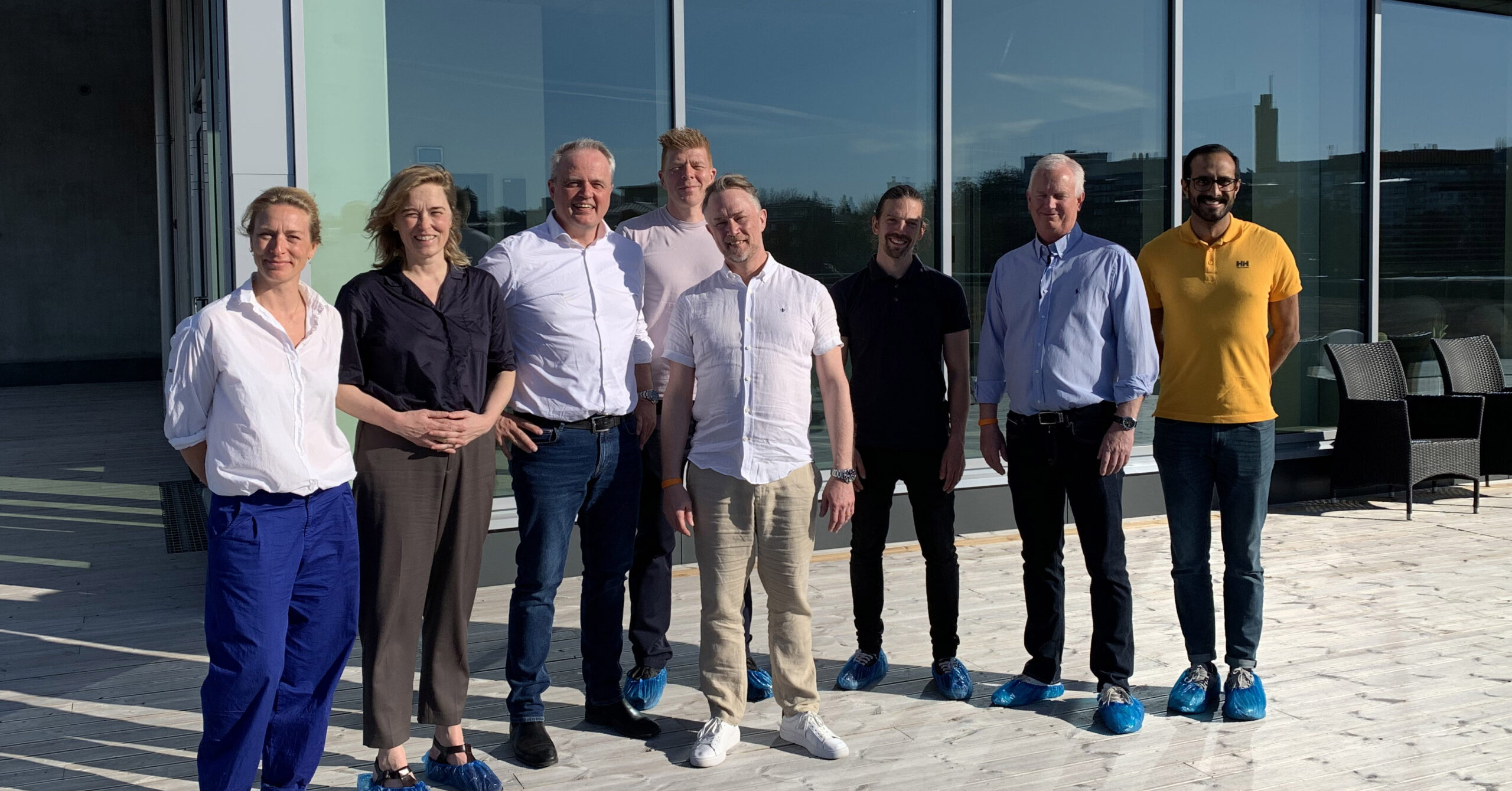 Projektteamet hos Lejonfastigheter och arkitekterna från arkitektbyrån 3XN i Danmark står på terrassen utanför simhallens relaxvåning.